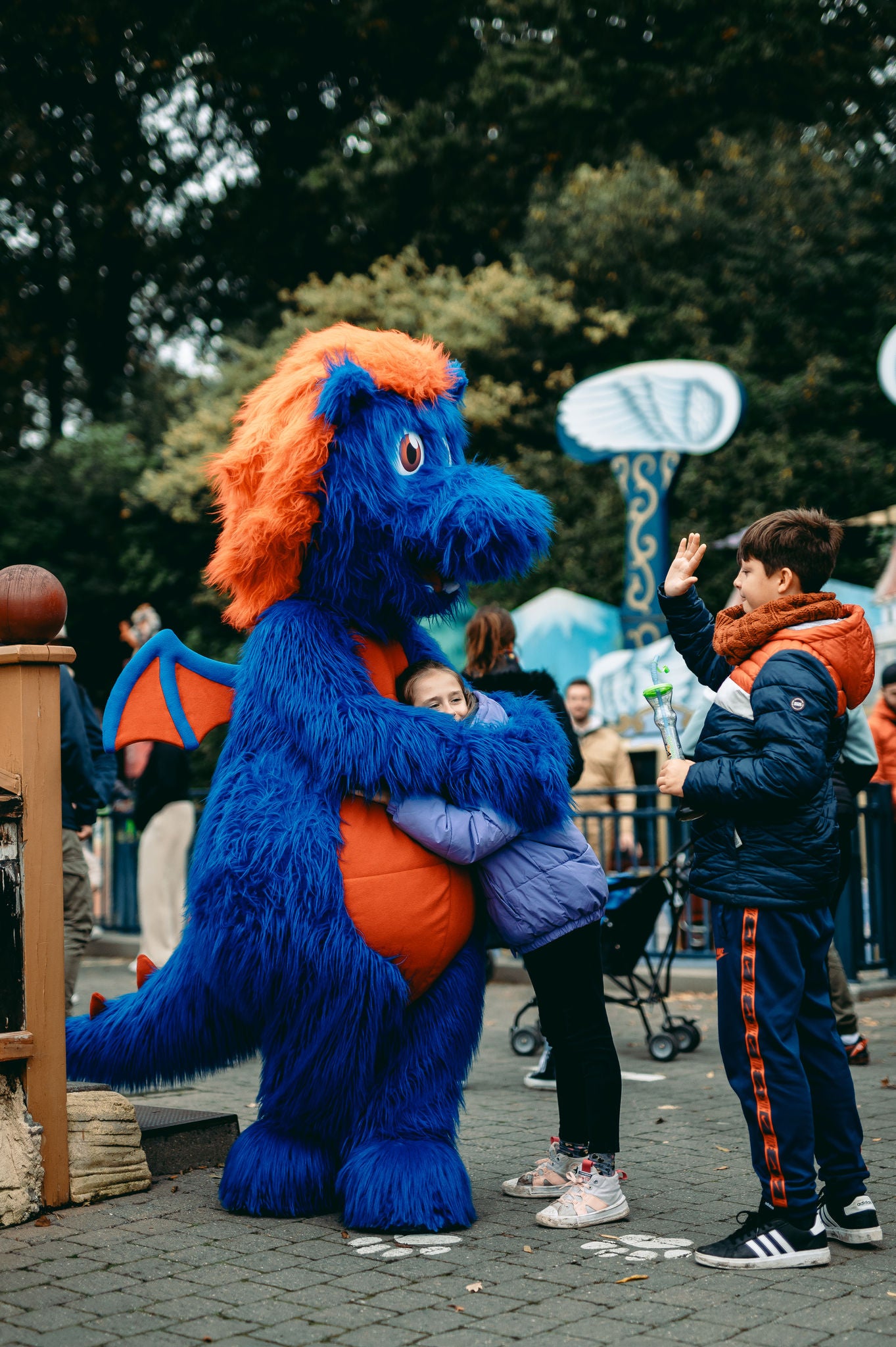 Draak Maric geeft een meisje een knuffel tijdens King’s Fest. Een jongen staat ondertussen klaar om een high five te geven.