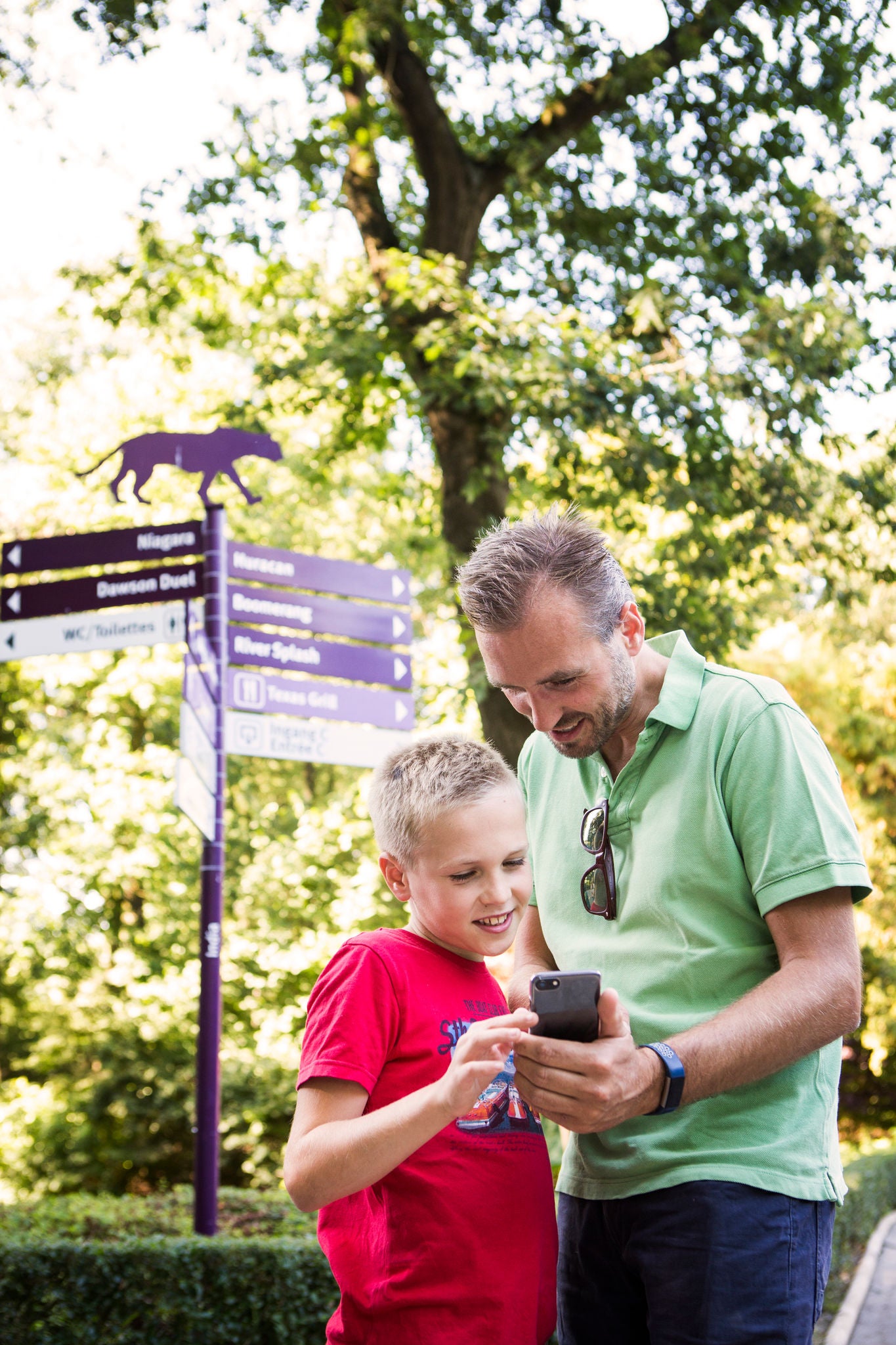 Papa en zoon ontdekken de Bellewaerde app op hun smartphone.
