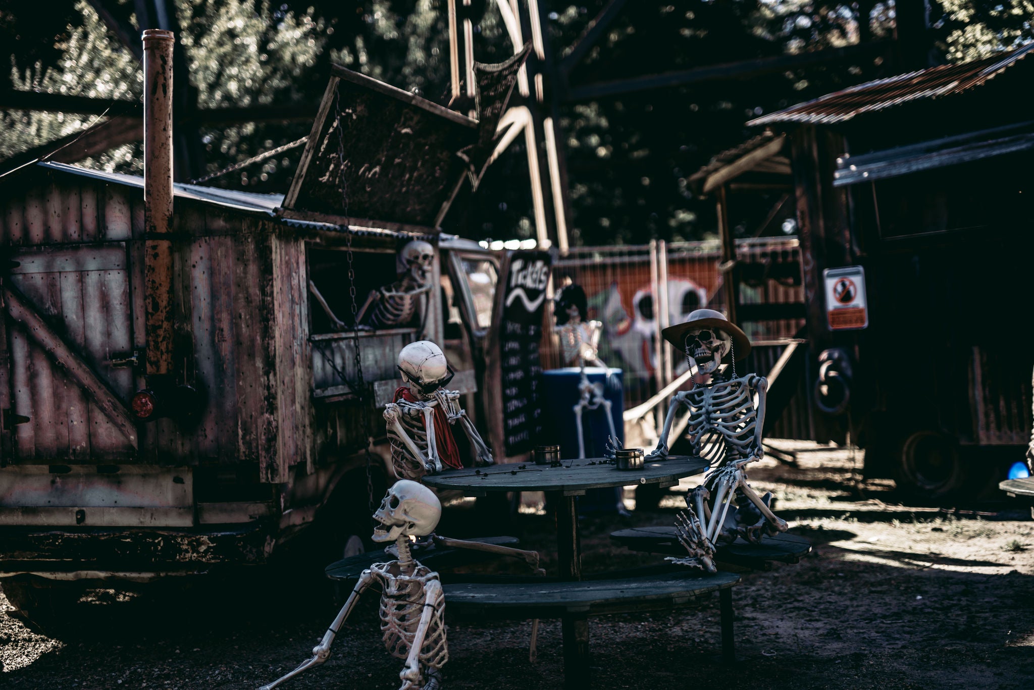 Skeletten zitten aan een picknick bank voor een foodtruck als Halloween decoratie.